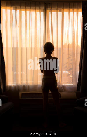 Rearview of boy looking out of window Stock Photo