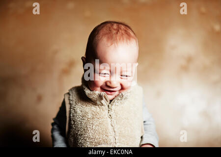 Portrait of cute baby boy looking down and giggling Stock Photo