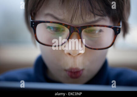 Close up of boy pulling a face using digital tablet Stock Photo