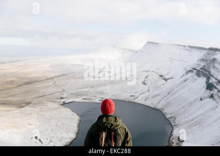 Rear view of man looking at Llyn y Fan Fach, The Brecon Beacons, Wales, UK Stock Photo