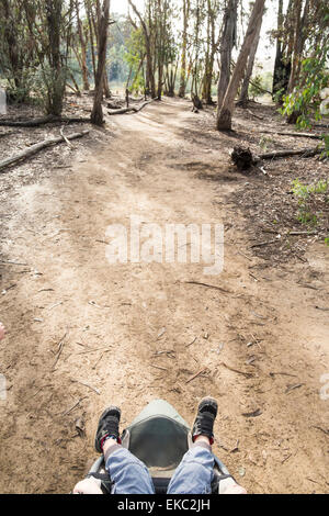 Boy's legs sticking out buggy in woods, overhead view