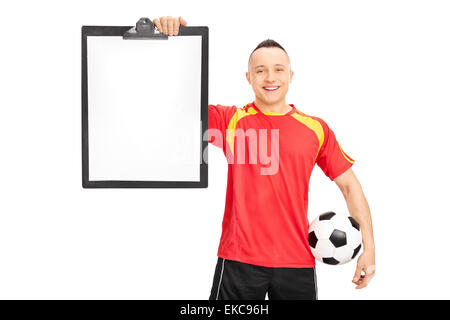 Young football player in a red and yellow jersey, holding a clipboard and a ball isolated on white background Stock Photo