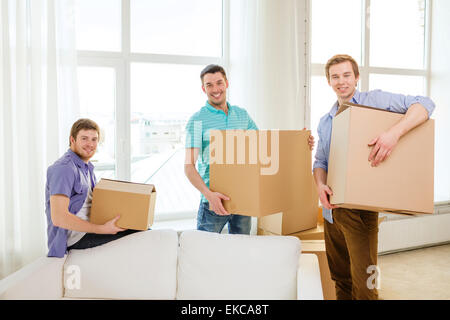 smiling male friends carrying boxes at new place Stock Photo