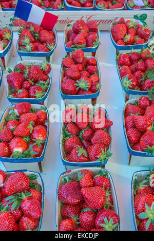 Punnets of fresh red strawberries laid out on a market stall in France with a French flag Stock Photo
