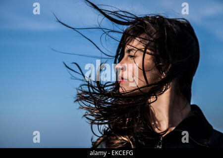 Young woman looking sideways with hair blowing in the wind