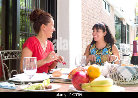 Two beautiful hispanic women enjoying an outdoor home meal together. Concept of family togetherness and outdoor dining. Stock Photo
