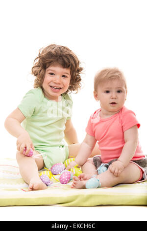 Happy little children boy and girl sitting and playing with Easter eggs Stock Photo