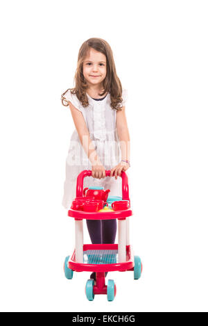 Little girl playing waiter and  pushing trolley pram with cups and kettle isolated on white background Stock Photo