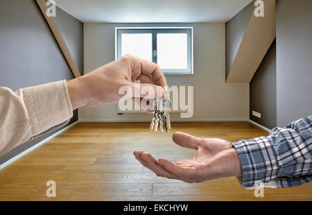 Realtor giving house key to buyer in empty room Stock Photo