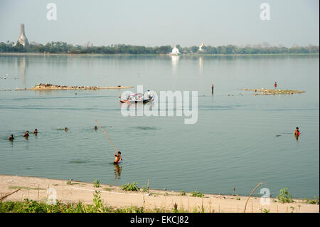 Fishermen beat the surface and wade through the water of a lake to catch fish in Amarapura near Mandalay Myanmar Stock Photo