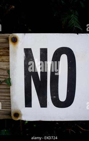 Close up of word NO, black on white background attached to wooden fence post. Stock Photo