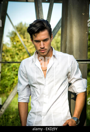 Handsome young man leaning against metal electricity trellis Stock Photo