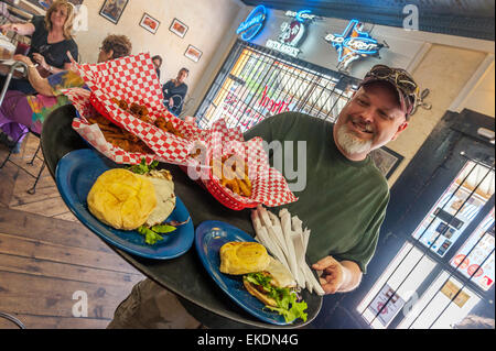 A smiling waiter carrying a tray of burgers and sandwiches at the Cowboy Gelato Smokehouse. Historic Route 66. Amarillo. Texas. USA Stock Photo