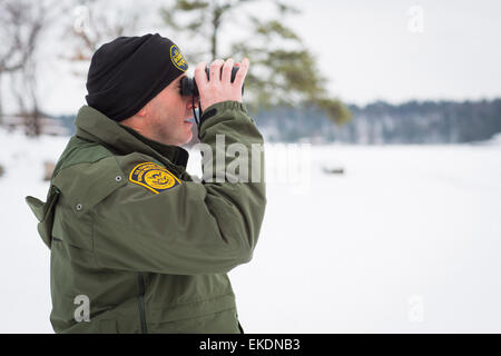 CBP Office of Border Patrol conducts cold weather operations in the Wellesley Island, Alexandria Bay and Clayton region of New York along the border of the United States and Canada. A Border Patrol Agent scans the area with high powered binoculars.  James Tourtellotte Stock Photo