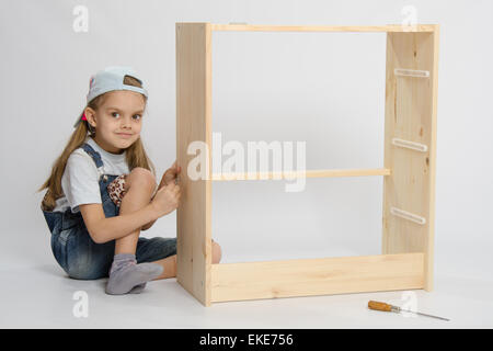 Little girl - collector of furniture twists the screw on the dresser Stock Photo