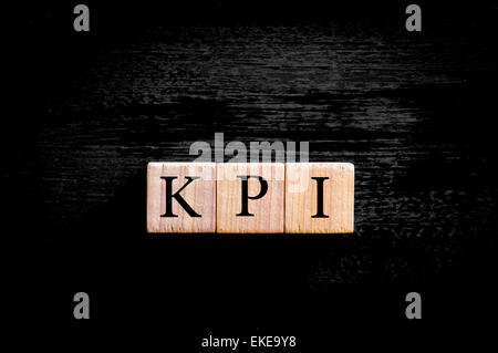Acronym KPI - key performance indicator. Wooden small cubes with letters isolated on black background with copy space available. Business Concept image. Stock Photo