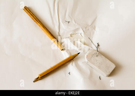 A broken pencil on a torn paper surrounded by bits of a used eraser Stock Photo