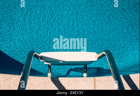 Looking down at swimming pool steps into inviting aqua blue water. Stock Photo