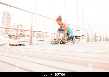 Young athletic girl tying up her running shoe laces for a morning run Stock Photo