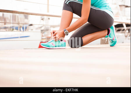 Close up of girl tying her running shoe laces at sunrise Stock Photo