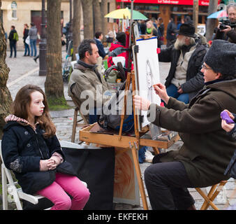 Unidentified artist drawing a portrait of the tourist at Place du Tertre, Montmartre. Stock Photo