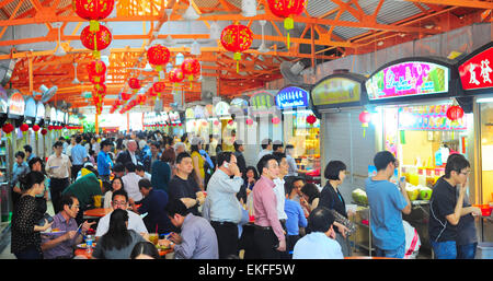 Locals eat at a popular food hall in Singapore. Inexpensive food stalls are numerous in the city so Stock Photo