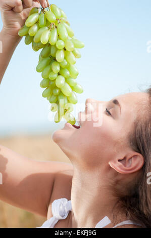 perfect woman eating grapes in wheat field. Picnic. Stock Photo