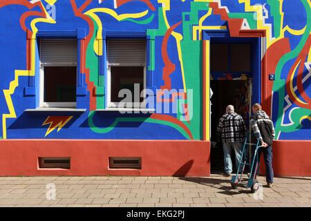 Two residents entering in their house in the colorful Otto Richter Street (Otto-Richter-Straße). Sudenburg, Magdeburg, Germany. Stock Photo