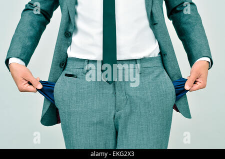 broke businessman wearing a gray suit showing his empty pockets Stock Photo