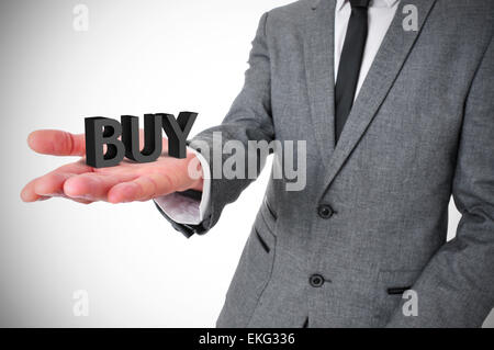 a young businessman wearing a gray suit shows the word buy, three-dimensional, in the palm of his hand Stock Photo