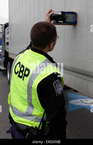 A CBP officer inspects a vehicle using a special device to check the ...