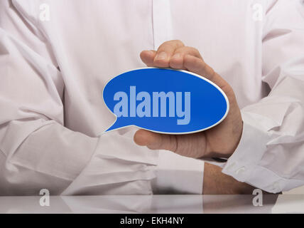 Image of a man hand holding empty blue speech balloon, white shirt and reflexion. Stock Photo