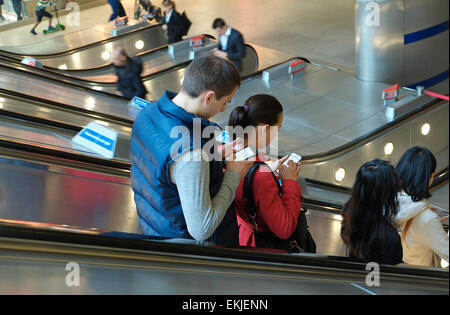 people using mobile phones on moving escalator, canary wharf, london, england Stock Photo