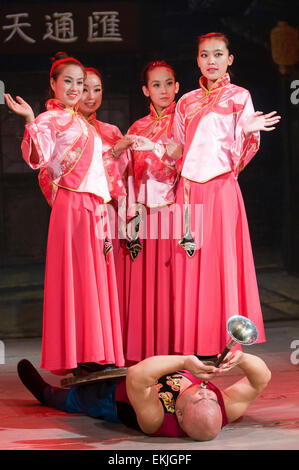 Performer plays horn as assistants stand on him during stage show in the ancient walled city of Pingyao, Shanxi Province, China Stock Photo