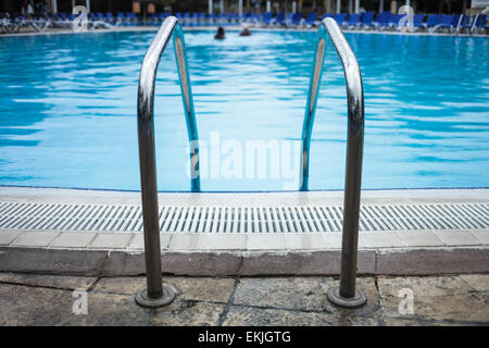 Swimming Pool Ladder Close-up with blurry people in background Stock Photo