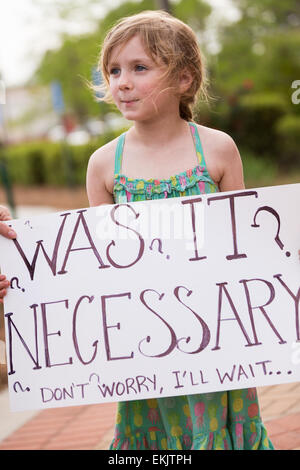 A young girl holds a sign during a vigil outside the North Charleston City Hall during a rally following the shooting death of Walter Scott April 10, 2015 in Charleston, South Carolina. Scott was shot multiple times by police after running from a traffic stop. Stock Photo