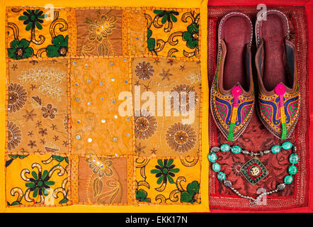 Colorful ethnic shoes, necklace and yellow Rajasthan cushion cover on flea market in India Stock Photo