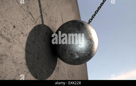 A regular metal wrecking ball attached to a chain hitting a concrete surface Stock Photo