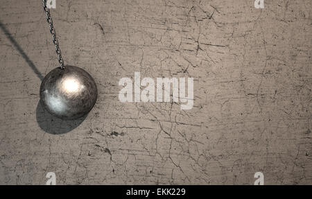 A regular metal wrecking ball attached to a chain hitting a concrete surface Stock Photo