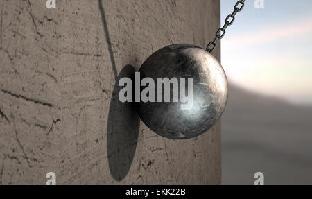 A regular metal wrecking ball attached to a chain hitting a concrete surface Stock Photo