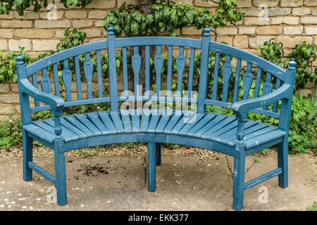 Blue wooden garden bench seat in front of old stone wall, Grimsthorpe Castle, Bourne, Lincolnshire, England, UK. Stock Photo