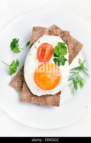 Fried egg, tomato slice and parsley on crispbread, top view Stock Photo