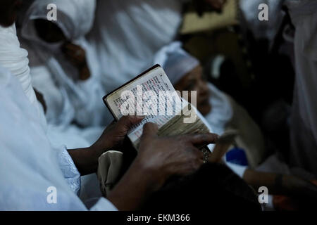 An Ethiopian Orthodox Christian pilgrim reading the bible in Amharic language during 'Holy Fire' ceremony inside the Ethiopian church beneath Deir El-Sultan monastery which is located on the roof of the Church of Holy Sepulchre in old city of Jerusalem Israel. Ethiopian Christians commemorate events around the crucifixion of Jesus Christ, leading up to his resurrection on Easter which in the Amharic language, is referred to as Fasika, originated from the Greek word Pascha. Stock Photo