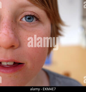 Close up portrait photo of boy with blue eyes and long hair against a blurred background Stock Photo