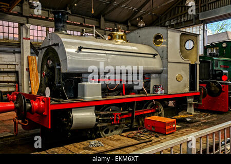 The gleaming saddle tank locomotive built by Peckett & Sons Ltd. in 1936 receiving some mechanical servicing at Chatham Dockyard Stock Photo