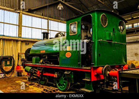 The gleaming saddle tank locomotive built by Peckett & Sons Ltd. in 1936 receiving some mechanical servicing at Chatham Dockyard Stock Photo
