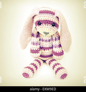 Knitted rabbit toy sitting over white background with soft shadow, vintage toned square photo with retro style toned effect Stock Photo