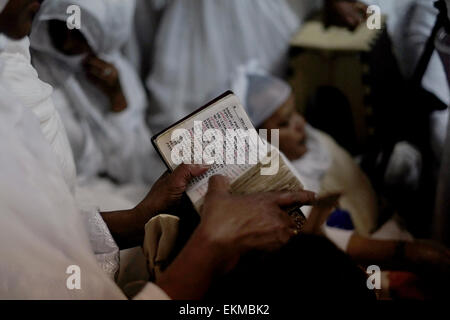 An Ethiopian Orthodox Christian pilgrim reading the bible in Amharic language during 'Holy Fire' ceremony inside the Ethiopian church beneath Deir El-Sultan monastery which is located on the roof of the Church of Holy Sepulchre in old city of Jerusalem Israel. Ethiopian Christians commemorate events around the crucifixion of Jesus Christ, leading up to his resurrection on Easter which in the Amharic language, is referred to as Fasika, originated from the Greek word Pascha. Stock Photo