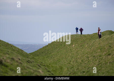 Wiltshire, UK. 12th April, 2015. UK Weather: Strong blustery winds high upon the landmark chalk White Horse above the town of Westbury. The strong winds did not stop many members of the public from visiting and making use of the weather to hike, walk pet dogs, fly kites and enjoy the stunning views across the Wiltshire vale.  The site is protected by English Heritage who maintain the ancient Iron Age hill fort seasonally by allowing grazing flocks of sheep to maintain favourable chalk grasses and scrub plants.   Credit:  Wayne Farrell/Alamy Live News Stock Photo