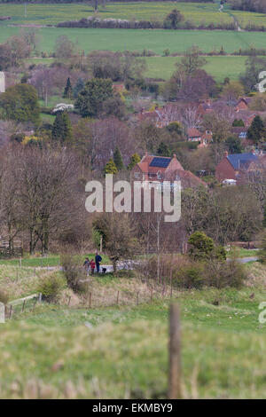 Wiltshire, UK. 12th April, 2015. UK Weather: Strong blustery winds high upon the landmark chalk White Horse above the town of Westbury. The strong winds did not stop many members of the public from visiting and making use of the weather to hike, walk pet dogs, fly kites and enjoy the stunning views across the Wiltshire vale.  The site is protected by English Heritage who maintain the ancient Iron Age hill fort seasonally by allowing grazing flocks of sheep to maintain favourable chalk grasses and scrub plants.   Credit:  Wayne Farrell/Alamy Live News Stock Photo